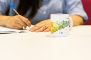 Person writing notes with a mug tea