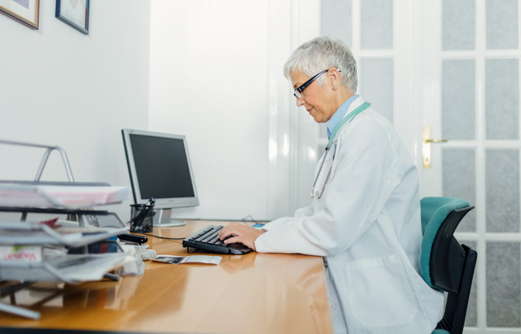 Female Doctor in her office, sitting and using computer.